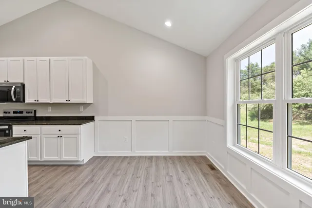 a kitchen with granite countertop white cabinets and wooden floor