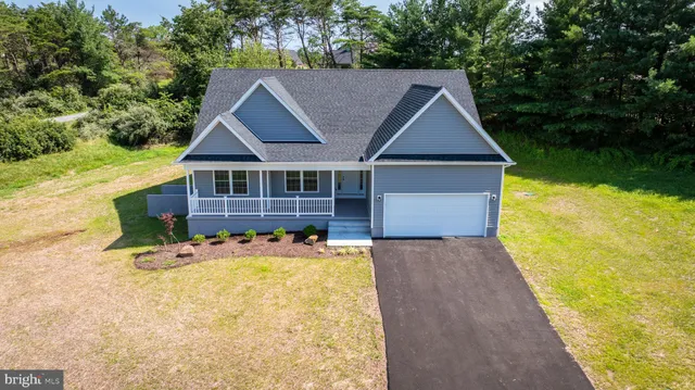a front view of house with yard and trees in the background