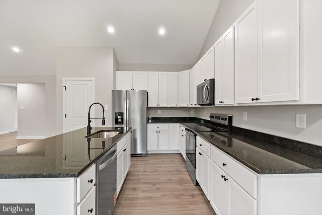 a kitchen with granite countertop white cabinets and stainless steel appliances
