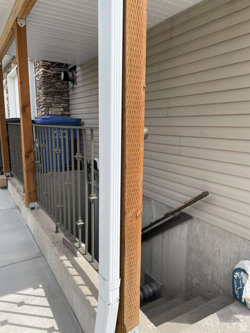 7030 West 2100 North Mendon, UT 84325 - Photo 54 of 67 Covered exterior walkway featuring a stone veneer accent wall, vinyl siding, and a metal railing
