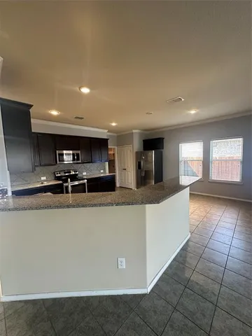 a large kitchen with stainless steel appliances a large counter top a stove and a refrigerator