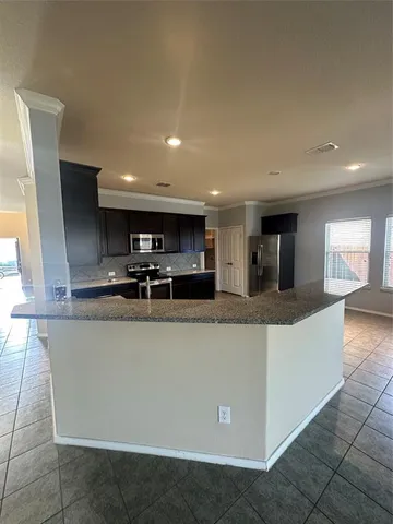 a large kitchen with stainless steel appliances a large counter top a stove and a refrigerator