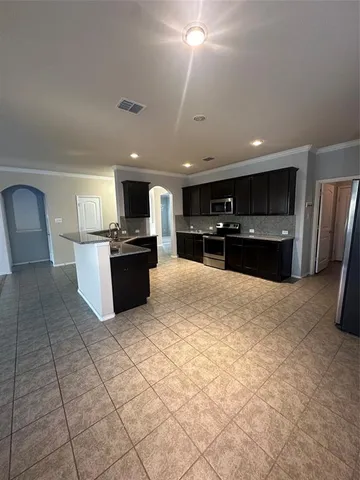 a large kitchen with kitchen island granite countertop a refrigerator and a stove top oven