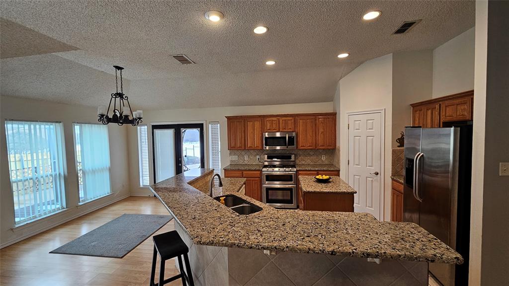 7529 Whitestone Ranch Road Benbrook, TX 76126 - Photo 10 of 26 a kitchen with stainless steel appliances granite countertop a stove refrigerator and a dining table with wooden floor