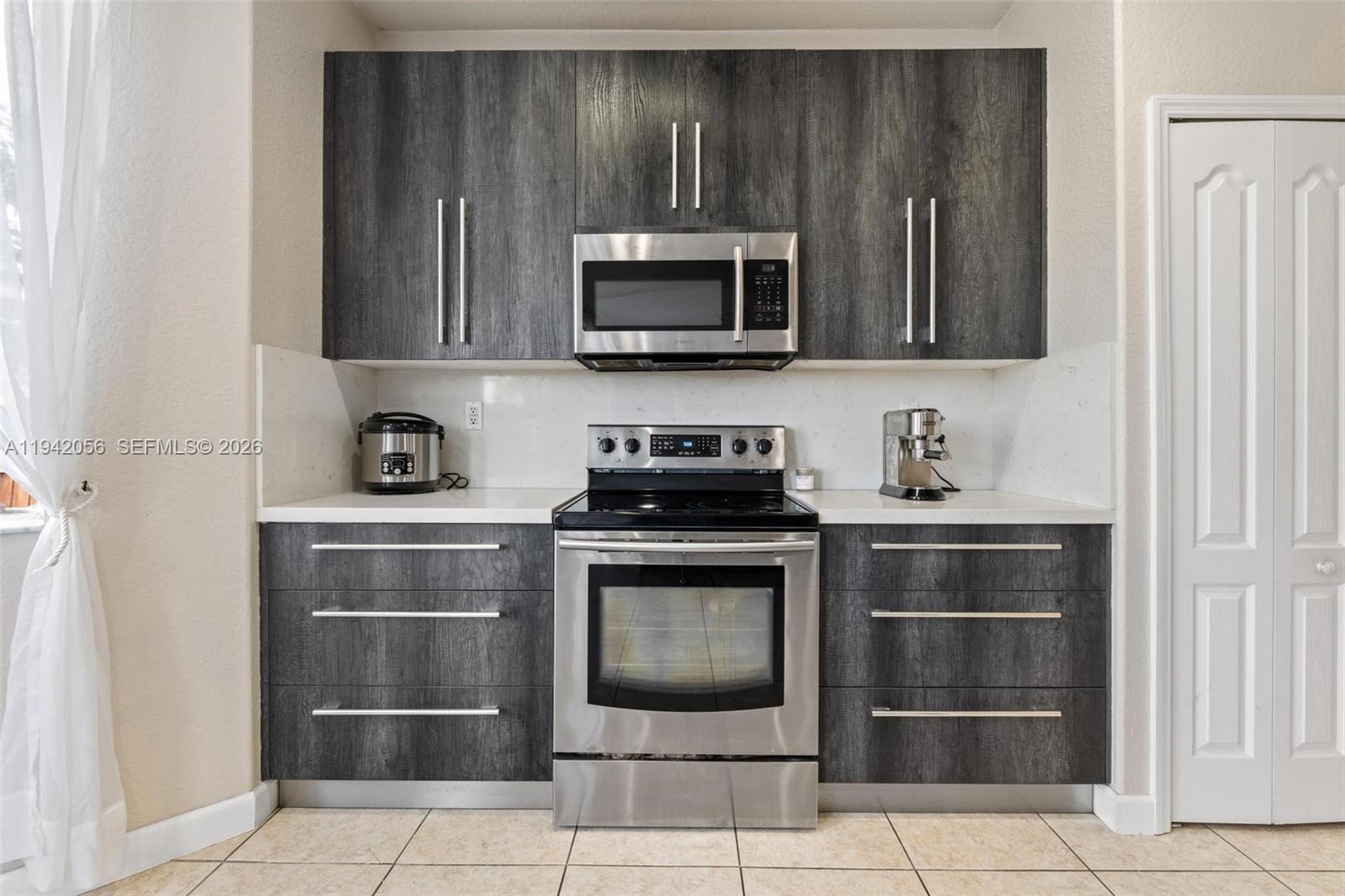16301 Southwest 70th Street Miami, FL 33193 - Photo 13 of 56 a kitchen with granite countertop a stove and a microwave with cabinets