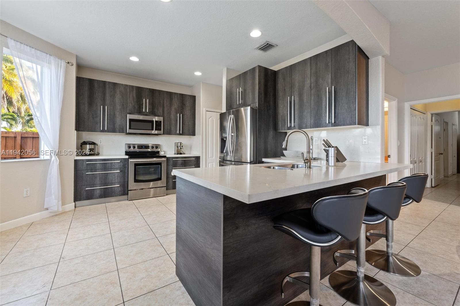 16301 Southwest 70th Street Miami, FL 33193 - Photo 16 of 56 a kitchen with kitchen island granite countertop a sink counter top space appliances and cabinets