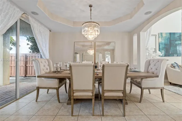 a dining room with furniture a chandelier and wooden floor