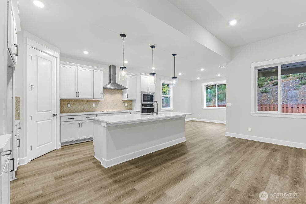 2538 Acer Loop Southeast Lacey, WA 98513 - Photo 4 of 13 a large kitchen with granite countertop a stove a sink a refrigerator and white cabinets with wooden floor