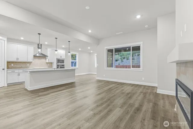 a large kitchen with kitchen island a stove a refrigerator a sink dishwasher and a fireplace with wooden floor