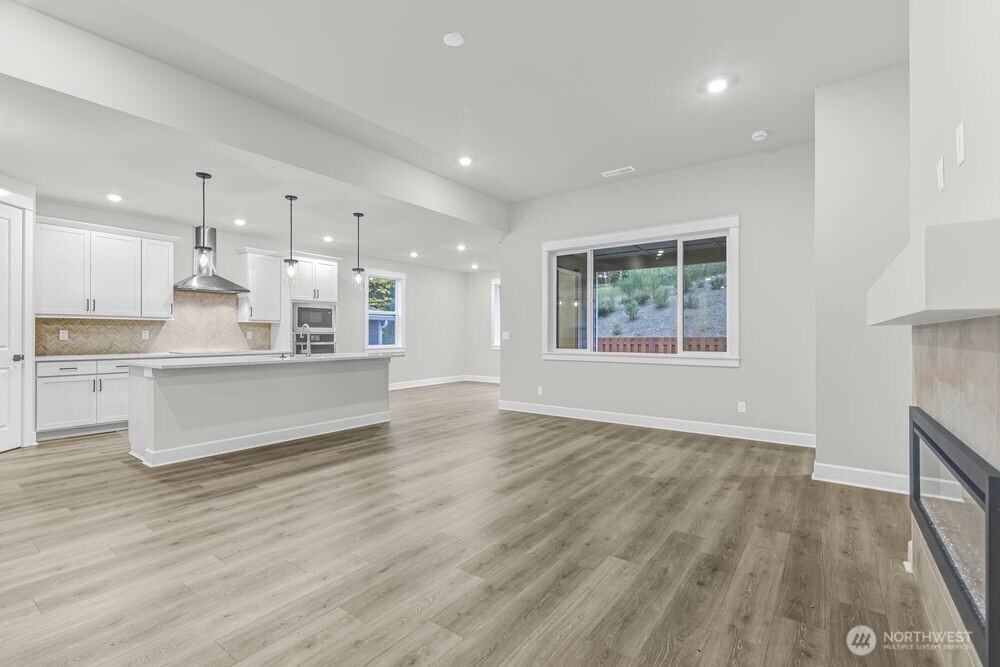 2538 Acer Loop Southeast Lacey, WA 98513 - Photo 6 of 13 a large kitchen with kitchen island a stove a refrigerator a sink dishwasher and a fireplace with wooden floor