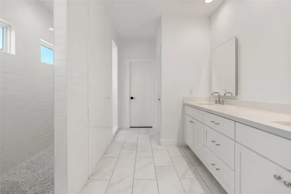 a spacious bathroom with a double vanity sink a mirror and a shower