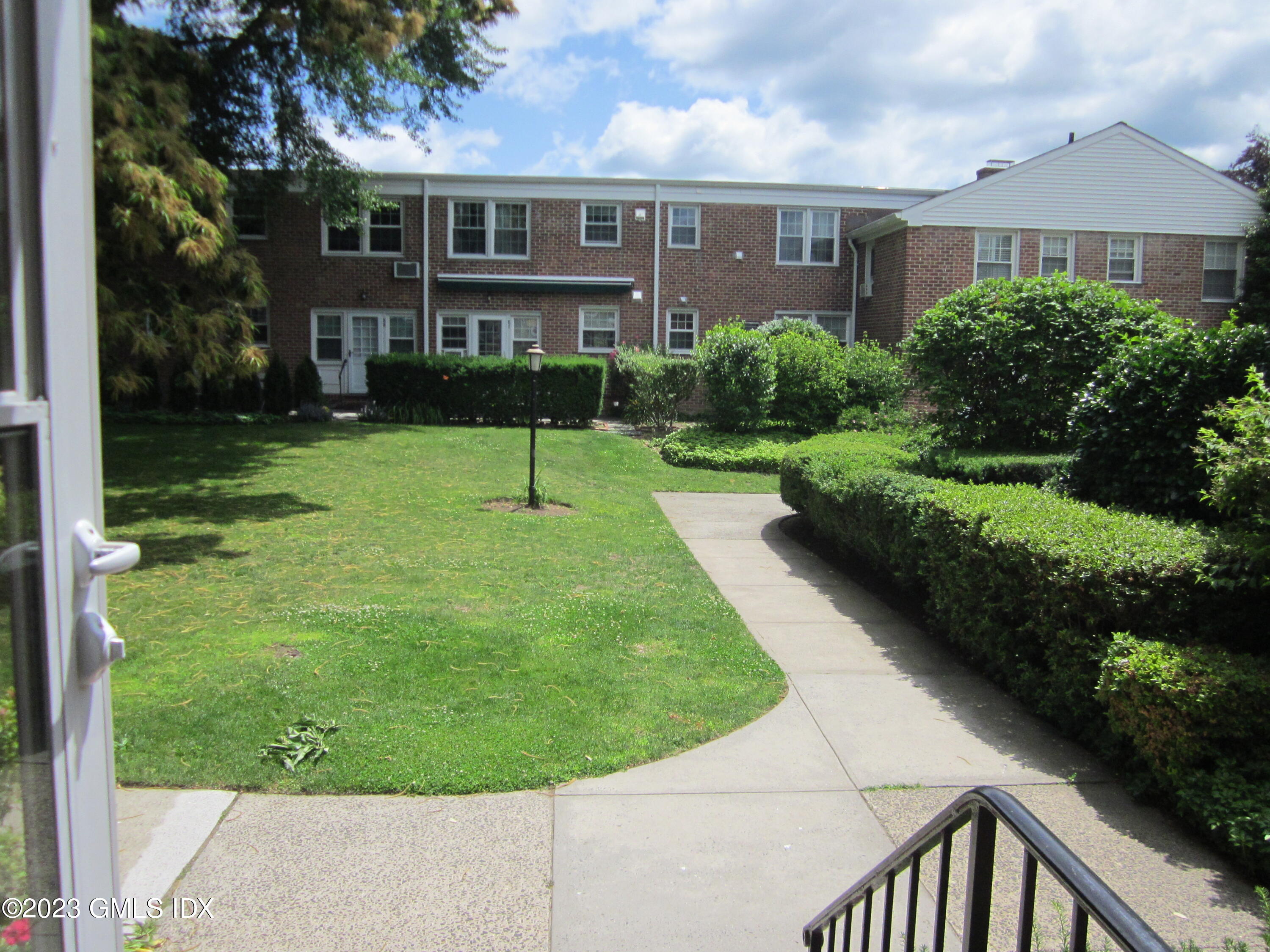 68 Putnam Park, Unit 68 Greenwich, CT 06830 - Photo 22 of 31 a view of a brick house with a yard and plants