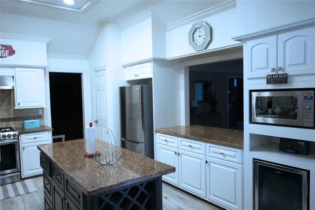 a kitchen with stainless steel appliances granite countertop a refrigerator a stove and a sink with wooden floor