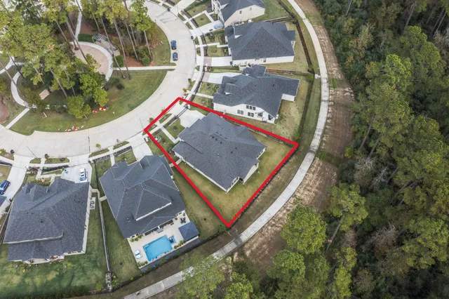 an aerial view of a swimming pool with a yard and plants