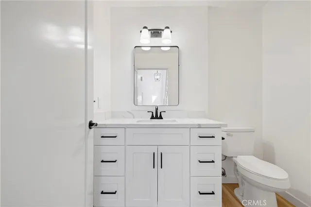 a bathroom with a toilet a sink a mirror and vanity