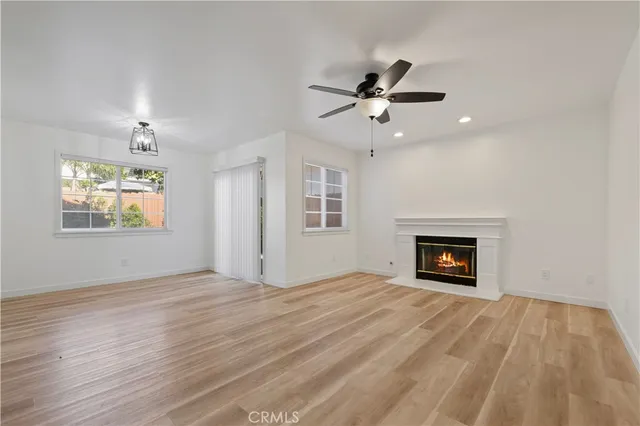 a view of empty room with wooden floor fireplace and a window