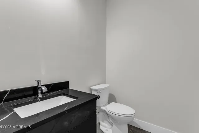a bathroom with a granite countertop toilet and sink