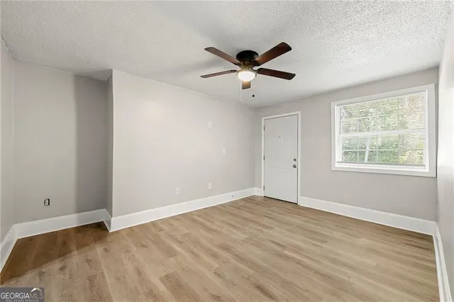 a view of empty room with wooden floor and fan