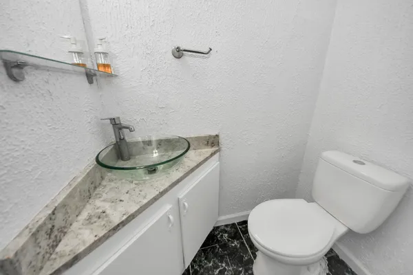 a bathroom with a granite countertop toilet and a sink