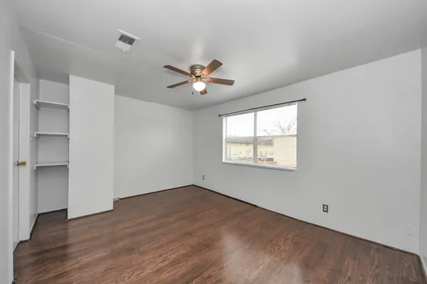 a view of an empty room with a window and wooden floor