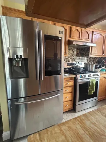 a kitchen with stainless steel appliances granite countertop a refrigerator a stove and a sink with wooden floor