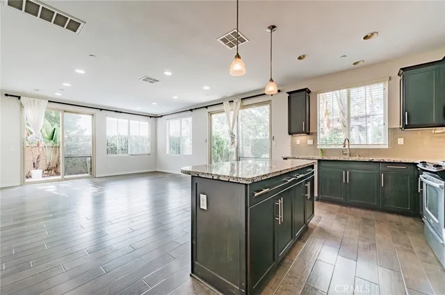 a kitchen with stainless steel appliances granite countertop a stove a sink and a refrigerator with wooden floor