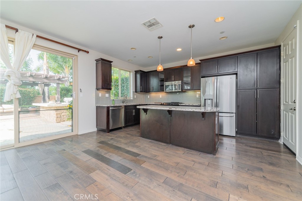 166 Desert Bloom Irvine, CA 92618 - Photo 6 of 36 a kitchen with stainless steel appliances granite countertop a refrigerator a sink dishwasher a stove and a refrigerator with wooden floor