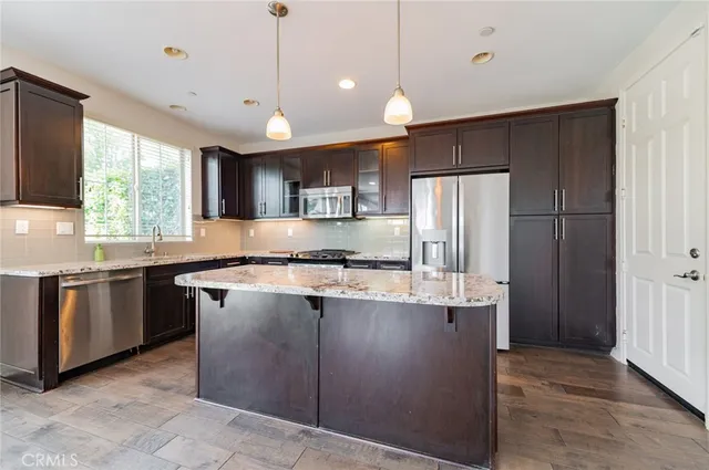 a kitchen with stainless steel appliances granite countertop a refrigerator a sink a stove a microwave and wooden cabinets