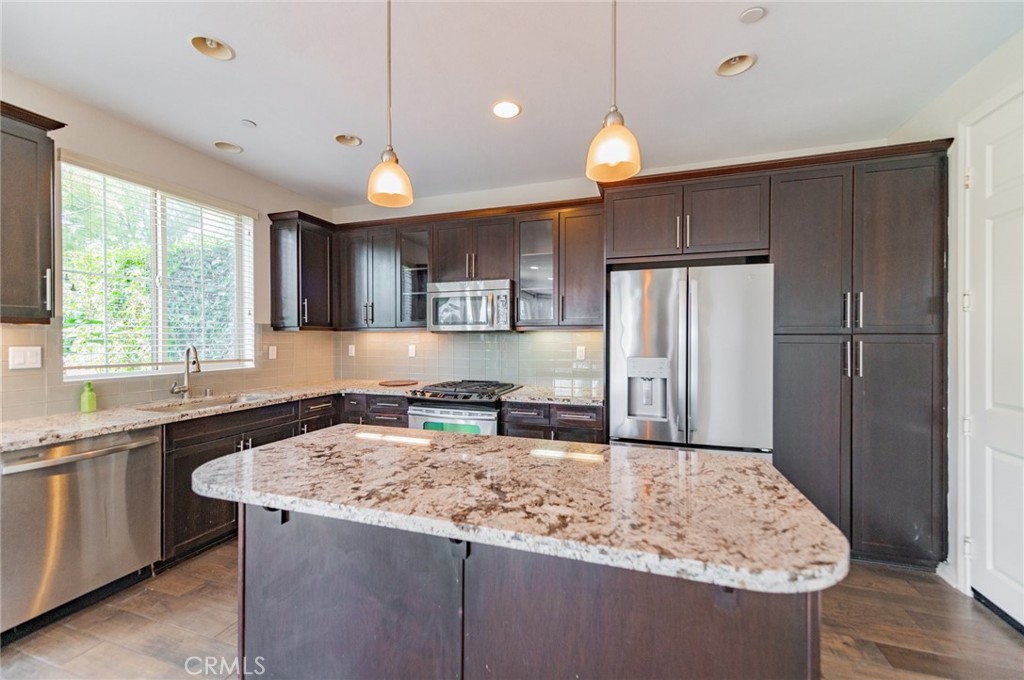 166 Desert Bloom Irvine, CA 92618 - Photo 10 of 36 a kitchen with kitchen island granite countertop a sink a counter space appliances and cabinets