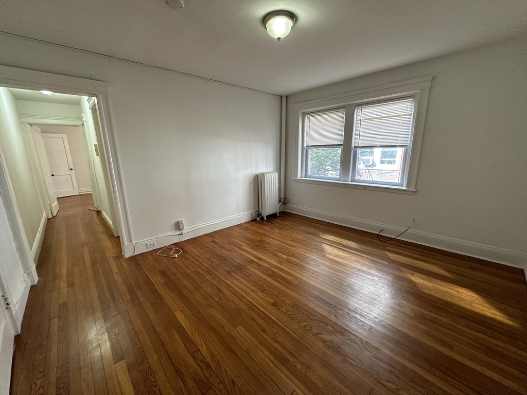 103 Summer Street, Unit 112 Malden, MA 02148 - Photo 2 of 6 an empty room with wooden floor and windows