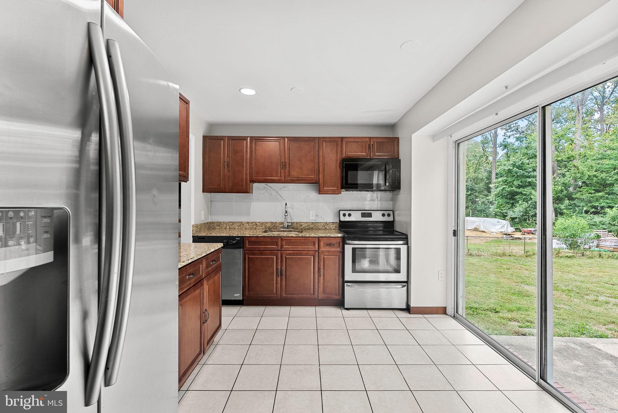 6313 Bardu Avenue Springfield, VA 22152 - Photo 12 of 26 a kitchen with a refrigerator a stove top oven a sink and a window