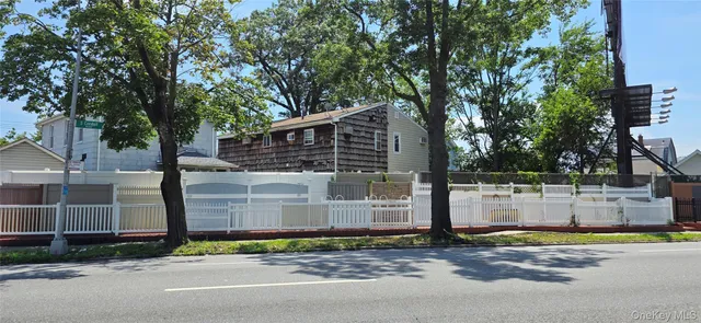 a view of a house with large tree and wooden fence
