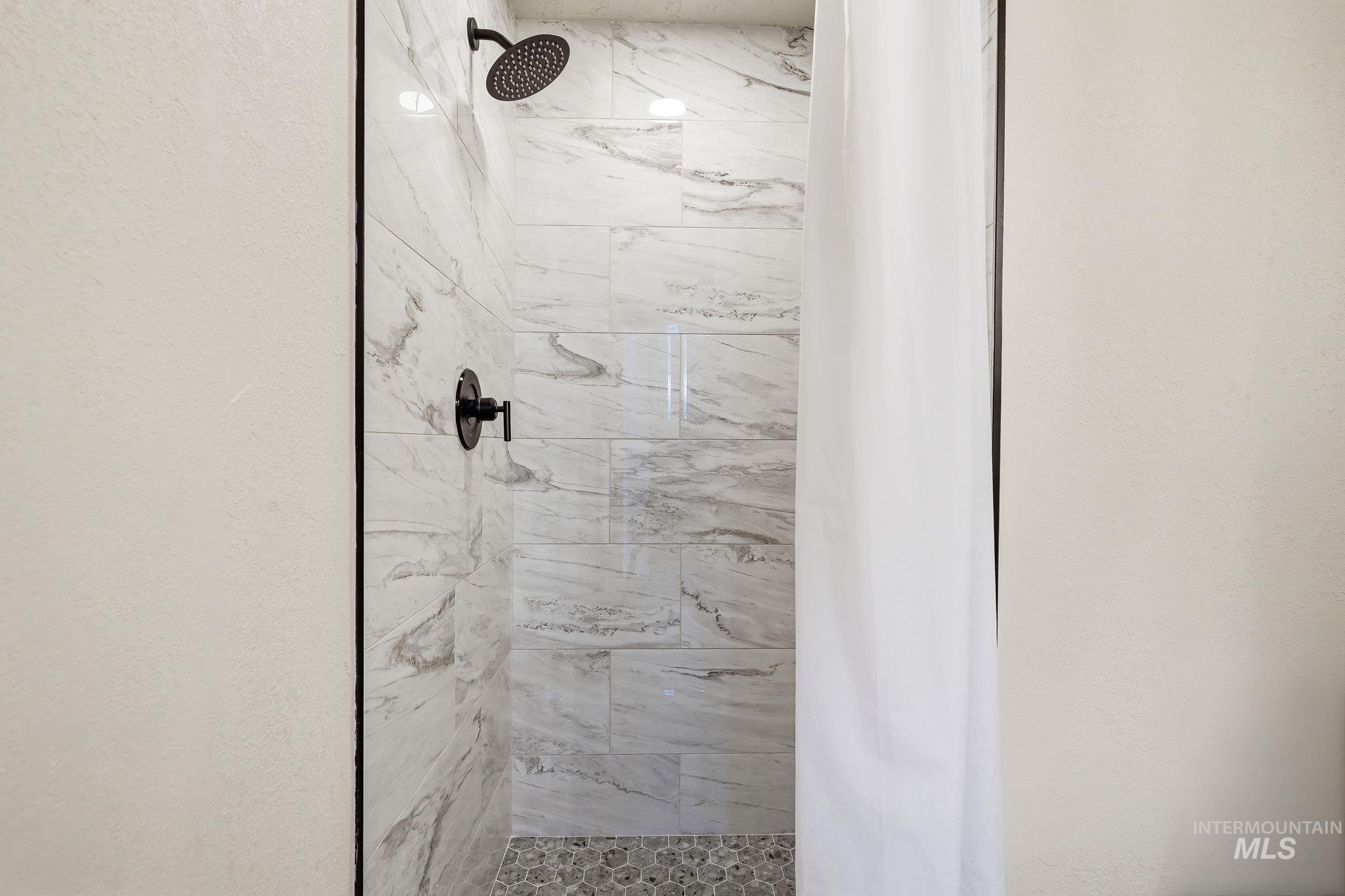 1990 Panama Street Boise, ID 83705 - Photo 41 of 50 Walk-in shower with matte black fixtures, textured wall tile, and a pebble floor