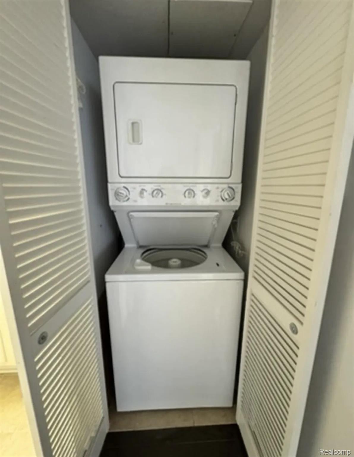 2247 Walton Blvd. Rochester, MI 48309 - Photo 12 of 12 Dedicated laundry area featuring a stacked washer and dryer unit, louvered bi-fold doors, and a tiled floor