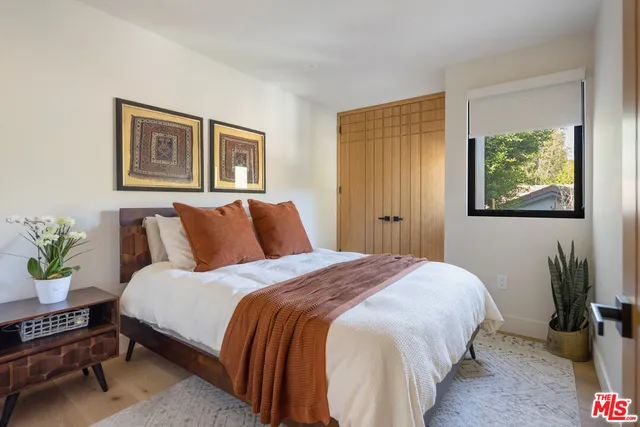 a bedroom with bed and two windows