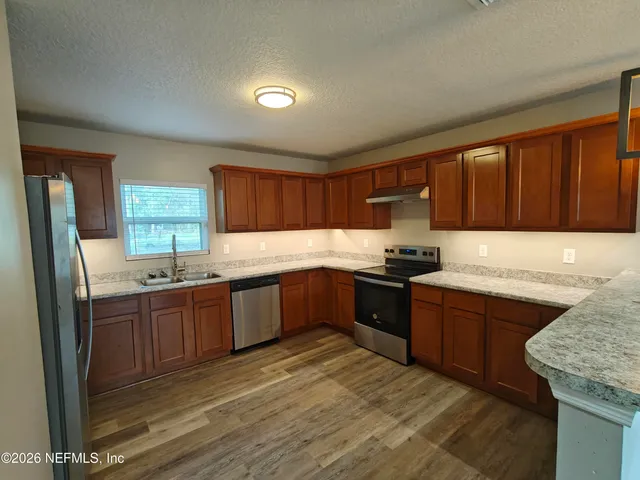 a kitchen with stainless steel appliances granite countertop wooden cabinets a stove top oven a sink and dishwasher
