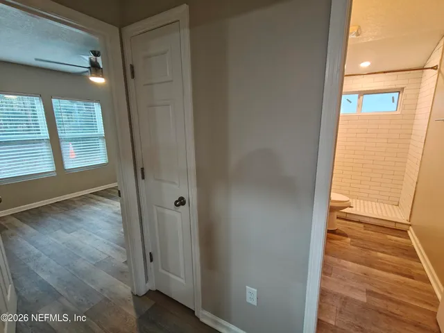 a view of a hallway with wooden floor and a bathroom
