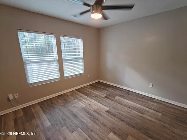 a view of empty room with wooden floor and fan