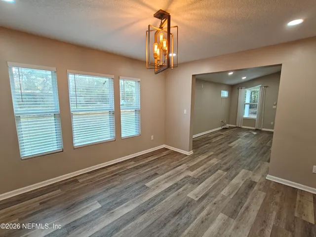 a view of an empty room with wooden floor and a ceiling fan