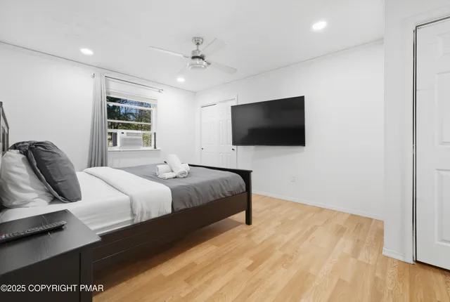 a bedroom with a bed tv and wooden floor