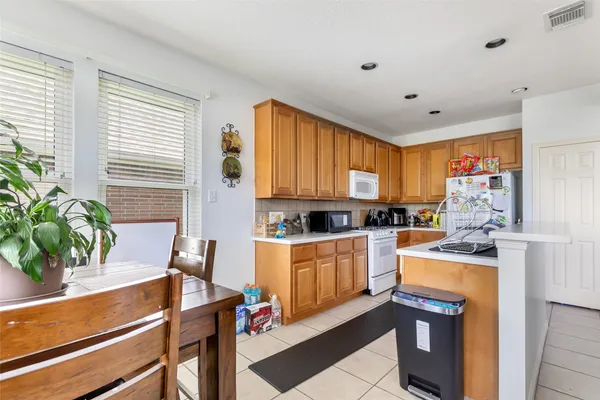 a kitchen with stainless steel appliances kitchen island granite countertop a refrigerator a stove a sink dishwasher and white cabinets with wooden floor