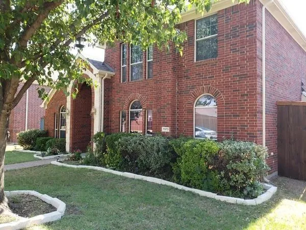 a brick building with a yard and a large tree