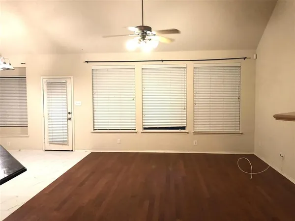 an empty room with wooden floor door and windows