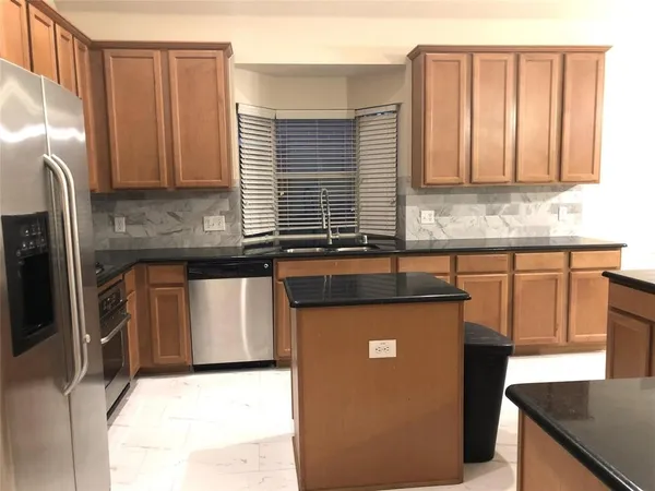 a kitchen with granite countertop a sink a stove and refrigerator