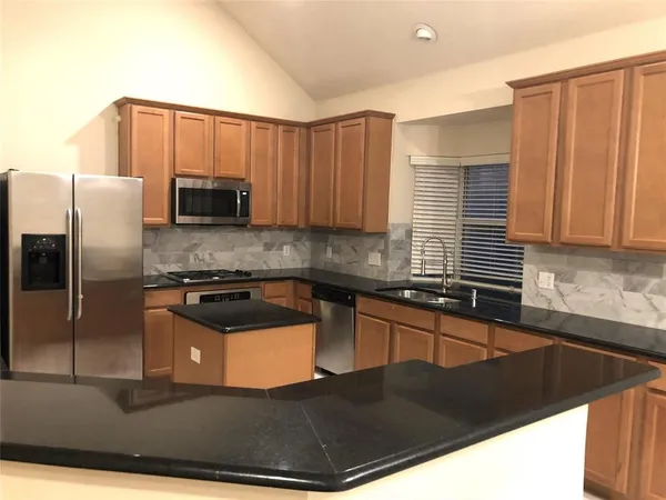 a kitchen with stainless steel appliances granite countertop a sink a stove and a refrigerator
