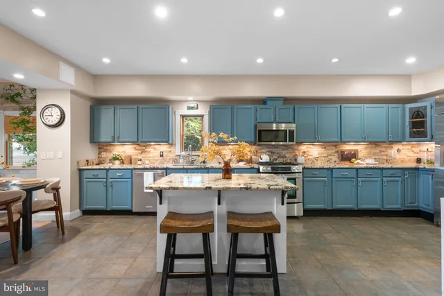 a kitchen with granite countertop a table chairs microwave oven stove and cabinets