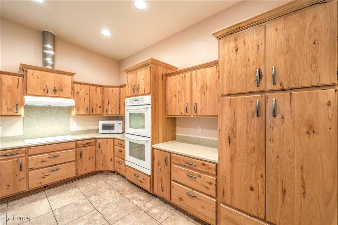 3910 West Pebble Road Las Vegas, NV 89139 - Photo 32 of 59 Guest house Kitchen featuring light countertops, white appliances, light tile patterned floors, under cabinet range hood, and recessed lighting