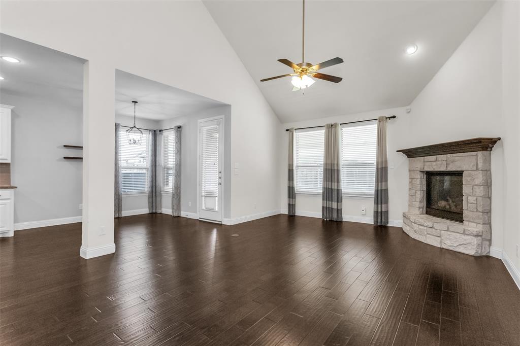 15713 Canyon Ridge Prosper, TX 75078 - Photo 13 of 38 Spacious living area featuring high vaulted ceilings, rich wood-finish flooring, and a stone fireplace with a substantial wood mantel