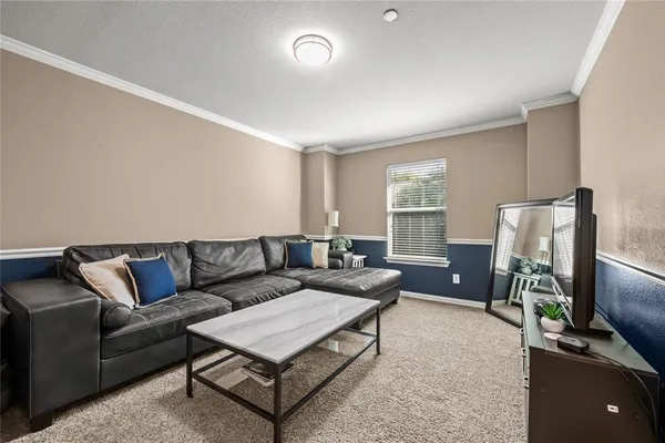 a living room with furniture a flat screen tv and a window