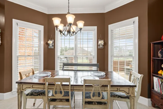 a view of a dining room with furniture a chandelier and a large window